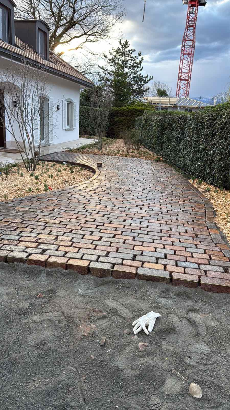Cheminement courbe en pavés devant une maison et un jardin